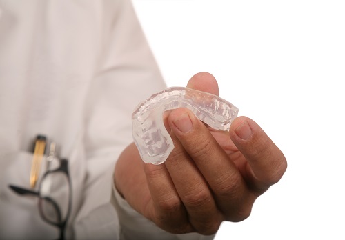 Dentist holding a night guard at For You Dental in Dallas, TX