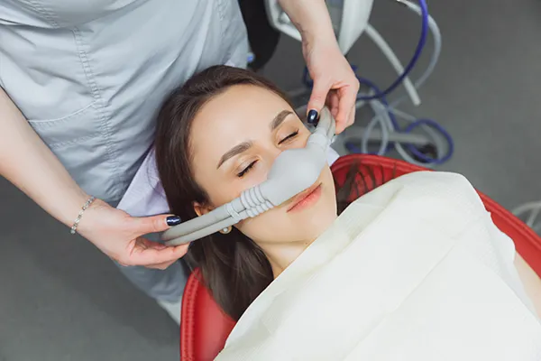 Female patient receiving sedation from mask at For You Dental in Carrollton, TX